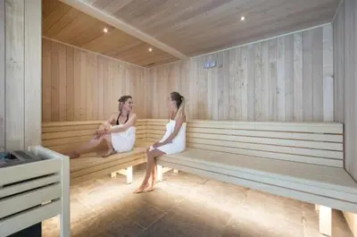 two women sitting on a bench in a sauna at Résidence Club MMV Samoens Village in Samoëns