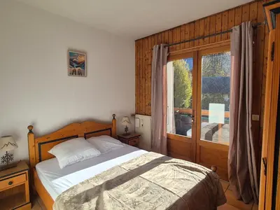 a bedroom with a bed and a large window at Appartement sud chaleureux, proche centre et ski, WIFI - FR-1-624-14 in Samoëns