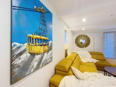 a room with a yellow couch and a painting on the wall at Chamonix Hyper centre . terrasse vue mont blanc . parking in Chamonix-Mont-Blanc