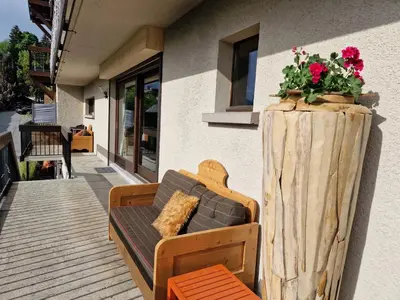 a couch sitting on a porch with a flower pot at Chalet du Vernay in Saint-Gervais-les-Bains