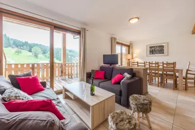 a living room with two couches and a table at L'Eden Ski aux Pieds in Morillon