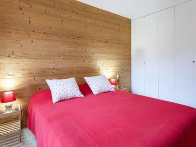 a bedroom with a red bed with a wooden wall at Apartment Le Diorama-3 by Interhome in Saint-Gervais-les-Bains