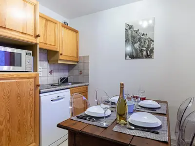 a kitchen with a table with plates and a bottle of wine at Apartment L'Espace Montagne-17 by Interhome in Chamonix-Mont-Blanc