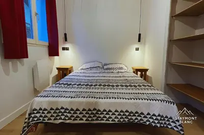 a bedroom with a bed with a black and white blanket at Charmant 2 pièces cosy au cœur de Saint-Gervais in Saint-Gervais-les-Bains