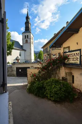 a building with a clock tower and a sign with flowers at Charmant 2 pièces cosy au cœur de Saint-Gervais in Saint-Gervais-les-Bains