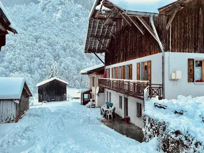 a building covered in snow next to a mountain at La Ferme De Fernand in Sixt