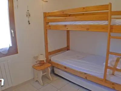 a bedroom with two bunk beds and a table at Appartement T3 cosy avec terrasse et parking, animaux admis, au pied de la navette ski-bus - FR-1-629-96 in Samoëns