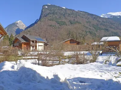 a house in the snow with mountains in the background at Appartement T3 cosy avec terrasse et parking, animaux admis, au pied de la navette ski-bus - FR-1-629-96 in Samoëns