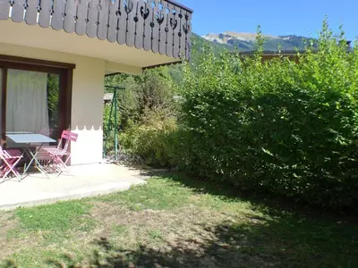 a house with a table and chairs next to a bush at Appartement T3 cosy avec terrasse et parking, animaux admis, au pied de la navette ski-bus - FR-1-629-96 in Samoëns
