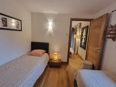 a bedroom with two beds and a light on the wall at appartement Shangrila in Chamonix-Mont-Blanc