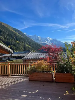 a wooden deck with some plants and mountains at appartement Shangrila in Chamonix-Mont-Blanc