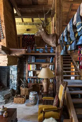 a living room with a staircase and a deer head on the wall at Arthaus Megève in Demi-Quartier