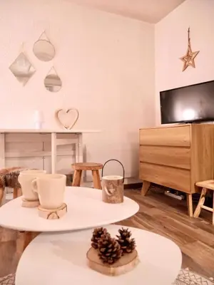 a living room with two tables and a tv at Cocon du Front de Neige in Demi-Quartier