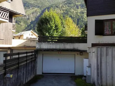 a building with a garage with a fence at Appartement calme avec garage privatif près du centre à Chamonix - FR-1-517-61 in Chamonix-Mont-Blanc