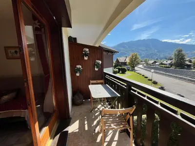 a balcony with a table and a view of the mountains at Appartement cosy proche centre et skibus, parking inclus - FR-1-624-90 in Samoëns
