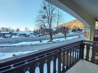 a balcony with a view of a snow covered street at Appartement cosy proche centre et skibus, parking inclus - FR-1-624-90 in Samoëns