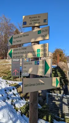 a street sign with signs on it in the snow at Studio sympa a saint Gervais les bains in Saint-Gervais-les-Bains