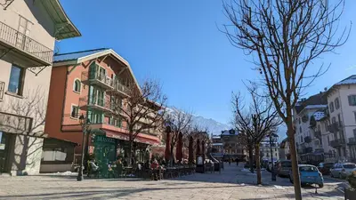 a city street with people sitting at tables on the sidewalk at Studio sympa a saint Gervais les bains in Saint-Gervais-les-Bains