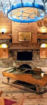 a room with a stone fireplace and a chandelier at Happy Moose - Cosy Mont Blanc View apartment with sauna in Chamonix-Mont-Blanc