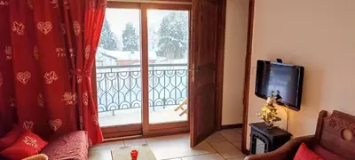 a living room with a television and a balcony at Happy Moose - Cosy Mont Blanc View apartment with sauna in Chamonix-Mont-Blanc