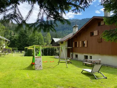 a living room with a black leather couch and a rug at Les Grangettes 2 - DUPLEX - WIFI gratuite in Les Carroz d'Araches
