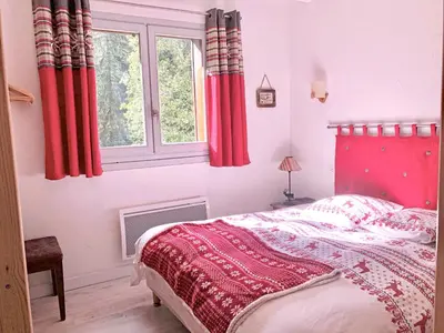 a bedroom with a bed with red curtains and a window at Chalet Rivière du Bon Nant Location de 6 à 14 personnes en Haute Savoie in Saint-Gervais-les-Bains