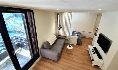 a living room with a couch and a television at Grand Studio Aiguille du Midi et vue Mont Blanc in Chamonix-Mont-Blanc
