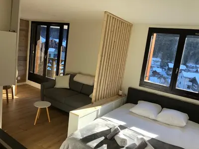 a small bedroom with a bed and a couch at Grand Studio Aiguille du Midi et vue Mont Blanc in Chamonix-Mont-Blanc