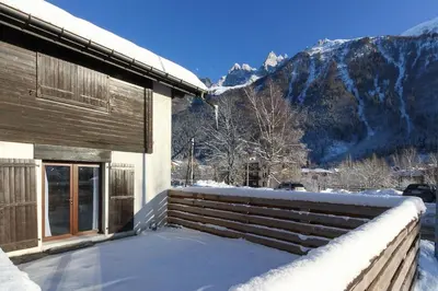a house in the snow with mountains in the background at Les Cîmes du Mont-Blanc in Chamonix-Mont-Blanc