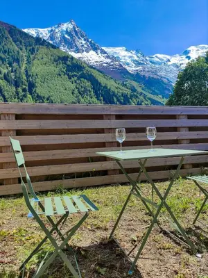 a table and a chair with two wine glasses at Les Cîmes du Mont-Blanc in Chamonix-Mont-Blanc