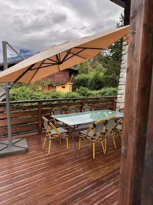 a table and chairs under an umbrella on a deck at Chalet Belle-Sofianna in Saint-Gervais-les-Bains