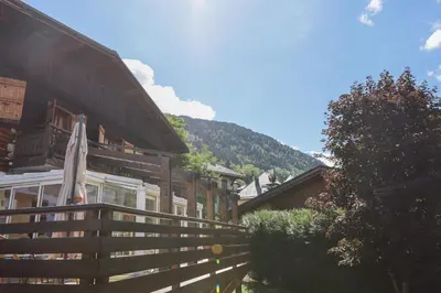 a building with a wooden fence and a mountain at Chalet Belle-Sofianna in Saint-Gervais-les-Bains