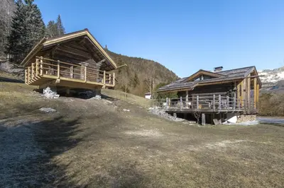 two large wooden buildings in a field with trees at Chalet L'Oratoire & Mazot - Renovated Historic Chalet - Huge Garden & Separate Cabin for 2 in Les Houches