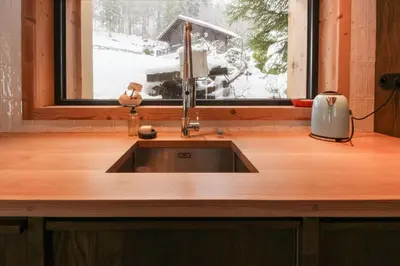 a kitchen sink in front of a window with snow at Chalet L'Oratoire & Mazot - Renovated Historic Chalet - Huge Garden & Separate Cabin for 2 in Les Houches