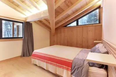 a bedroom with a bed and two windows at Chalet L'Oratoire & Mazot - Renovated Historic Chalet - Huge Garden & Separate Cabin for 2 in Les Houches