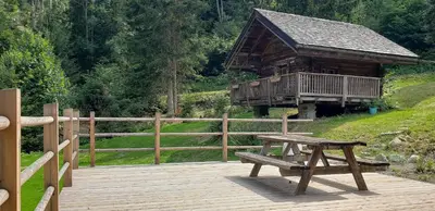 a wooden deck with a picnic table and a cabin at Chalet L'Oratoire & Mazot - Renovated Historic Chalet - Huge Garden & Separate Cabin for 2 in Les Houches