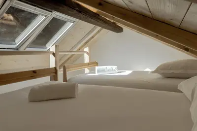 two beds in a attic room with two windows at Chalet L'Oratoire & Mazot - Renovated Historic Chalet - Huge Garden & Separate Cabin for 2 in Les Houches