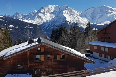 a log cabin with snow covered mountains in the background at Apartment With View On The Mont Blanc in Saint-Gervais-les-Bains