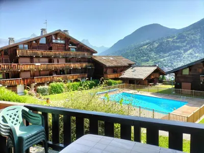 a hotel with a balcony with a swimming pool at Appartement meublé avec vue sur les montagnes et piscine l'été in Saint-Gervais-les-Bains