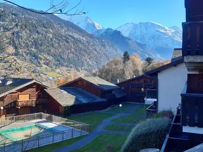 a view of a house with mountains in the background at Appartement meublé avec vue sur les montagnes et piscine l'été in Saint-Gervais-les-Bains