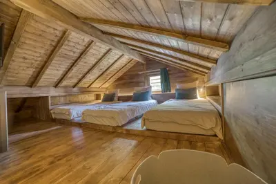 two beds in a room with wooden ceilings at Le Chalet Georges in Chamonix-Mont-Blanc