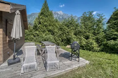 a deck with a grill and two chairs and an umbrella at Le Chalet Georges in Chamonix-Mont-Blanc