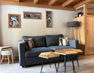 a living room with a blue couch and two tables at Résidence Grand Roc - Bruyères 20 in Chamonix-Mont-Blanc
