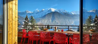 a table and chairs on a balcony with a view of mountains at New Spacious Appart. Incredible view of Mt Blanc in Passy