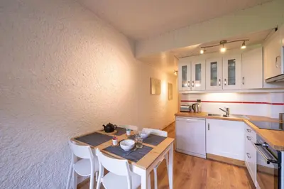 a kitchen with a wooden table and white cabinets at Cocon du Lachat in Saint-Gervais-les-Bains
