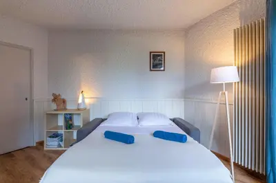 a large white bed with two blue pillows on it at Cocon du Lachat in Saint-Gervais-les-Bains