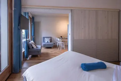 a bedroom with a white bed and a living room at Cocon du Lachat in Saint-Gervais-les-Bains