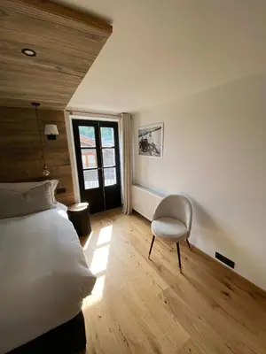 a bedroom with a bed and a chair and a window at Le Marti in Chamonix-Mont-Blanc