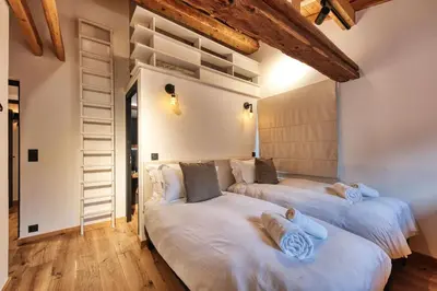 two beds in a room with wooden floors and wooden ceilings at Le Marti in Chamonix-Mont-Blanc