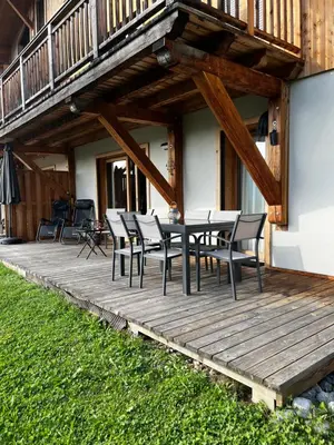 a wooden deck with a table and chairs on a house at Plein Soleil 3 bedroom apartment with stunning mountain views in Samoëns